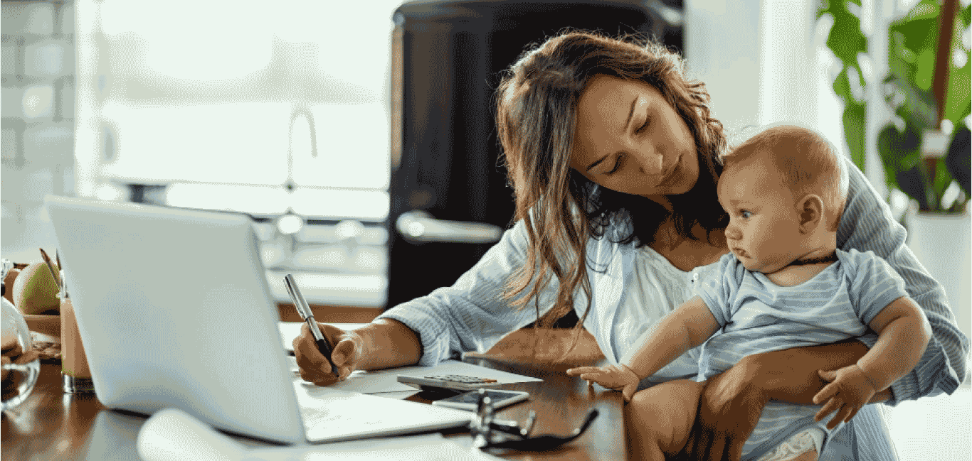 Madre trabajando desde casa con su bebé en brazos, representando el equilibrio entre maternidad y liderazgo profesional.